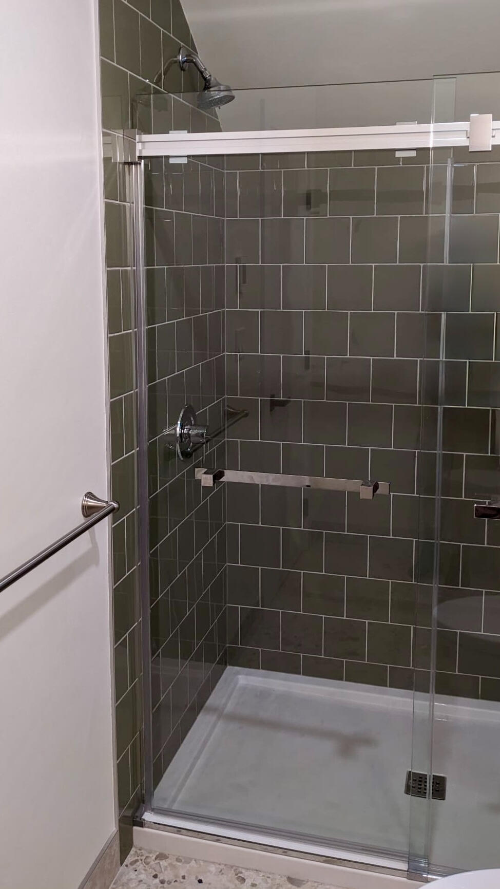 Custom walk-in shower featuring olive green subway tiles, sliding glass doors, and brushed nickel hardware