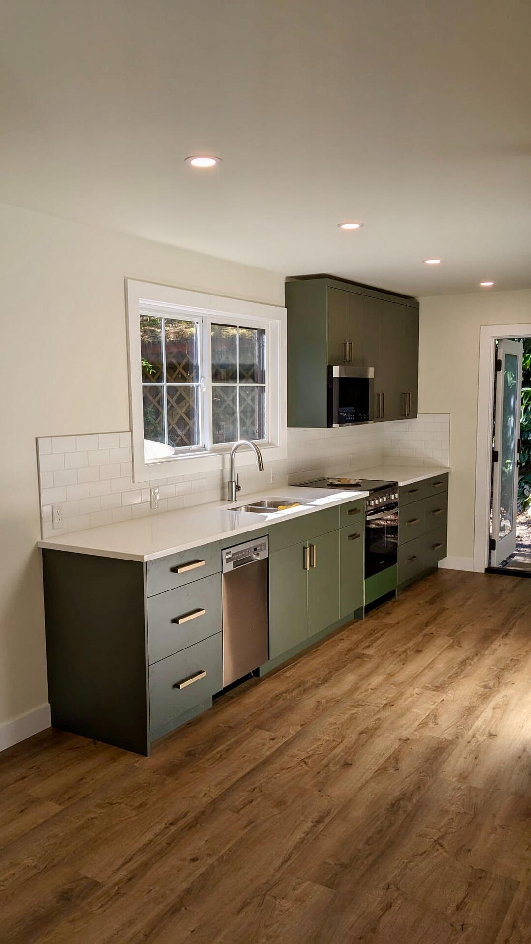 Modern kitchen design featuring olive green lower cabinets, stainless steel appliances, white quartz countertops, and subway tile backsplash.